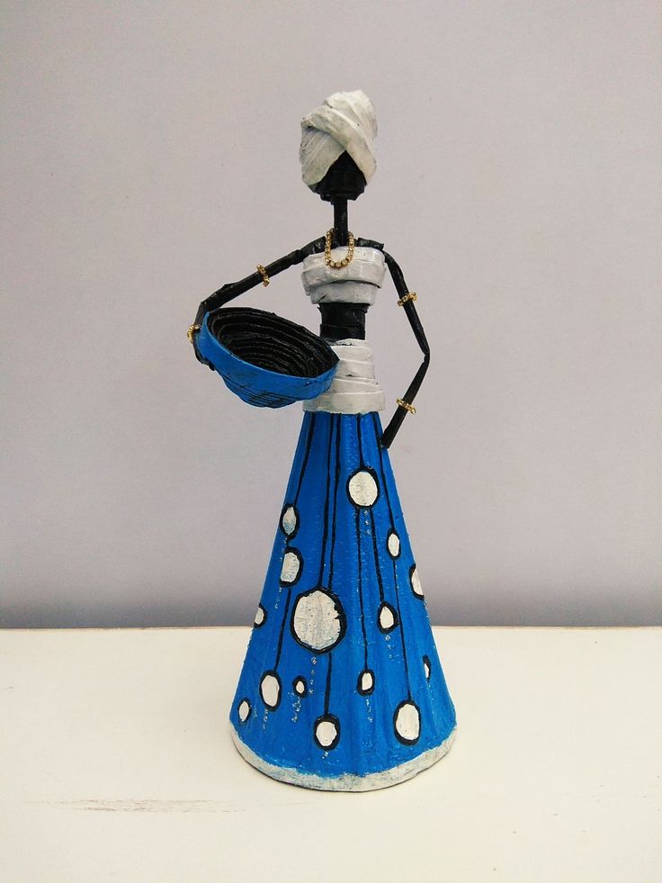 a blue and white ceramic figurine holding a bowl with polka dots on it