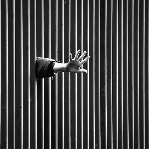 a person reaching out their hand to grab something in the air on top of a metal structure