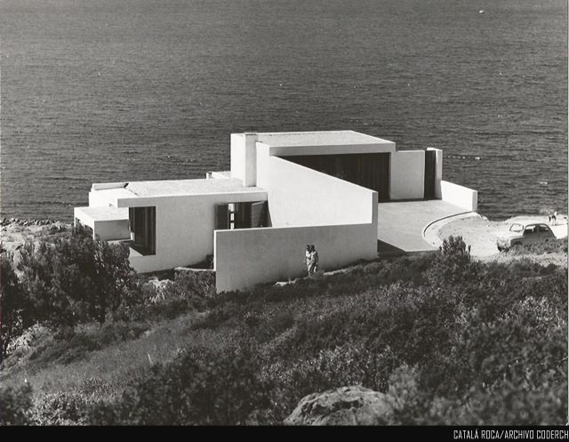 an old black and white photo of a house on the edge of a cliff by the ocean