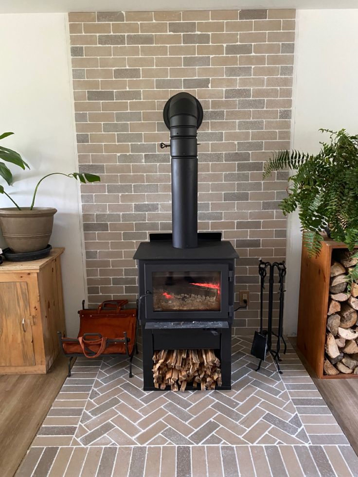 a wood burning stove sitting next to a pile of firewood