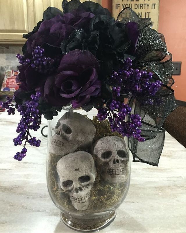 three skulls in a vase with purple flowers