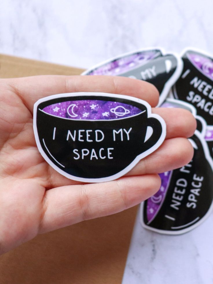 i need my space sticker in the palm of someone's hand with purple and black designs on it