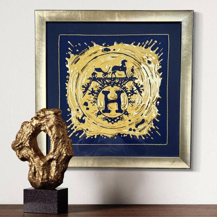 a gold and blue art piece sitting on top of a wooden table next to a golden sculpture