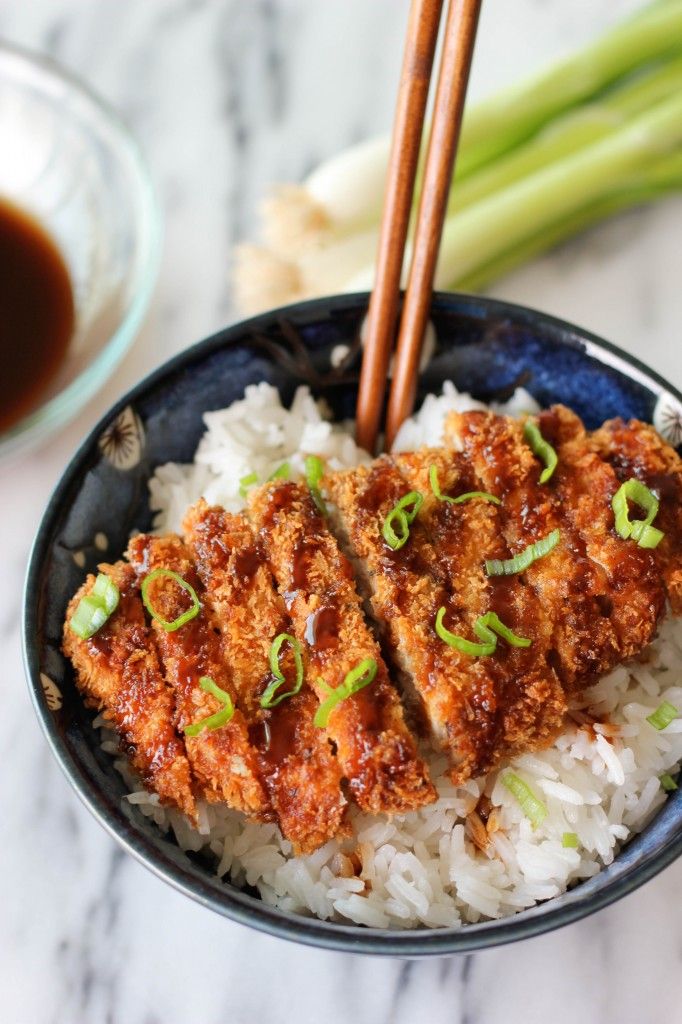 a bowl filled with rice and meat next to chopsticks on top of it