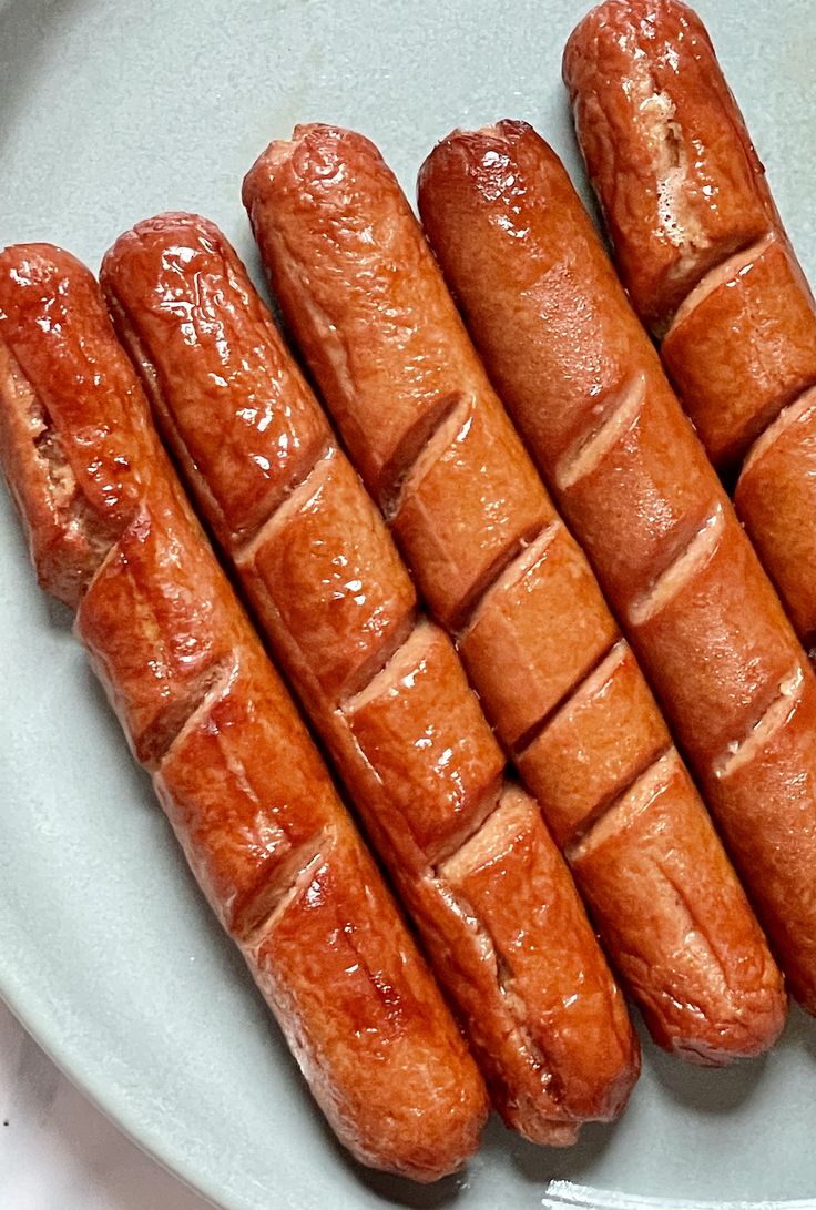 four hot dogs on a plate with ketchup