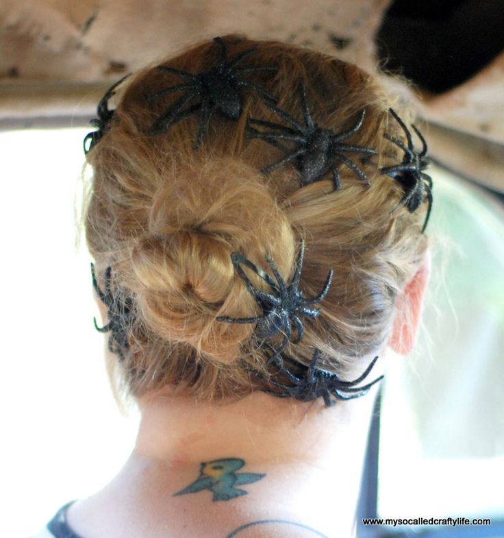 the back of a woman's head with spider webs on her hair and tattoos