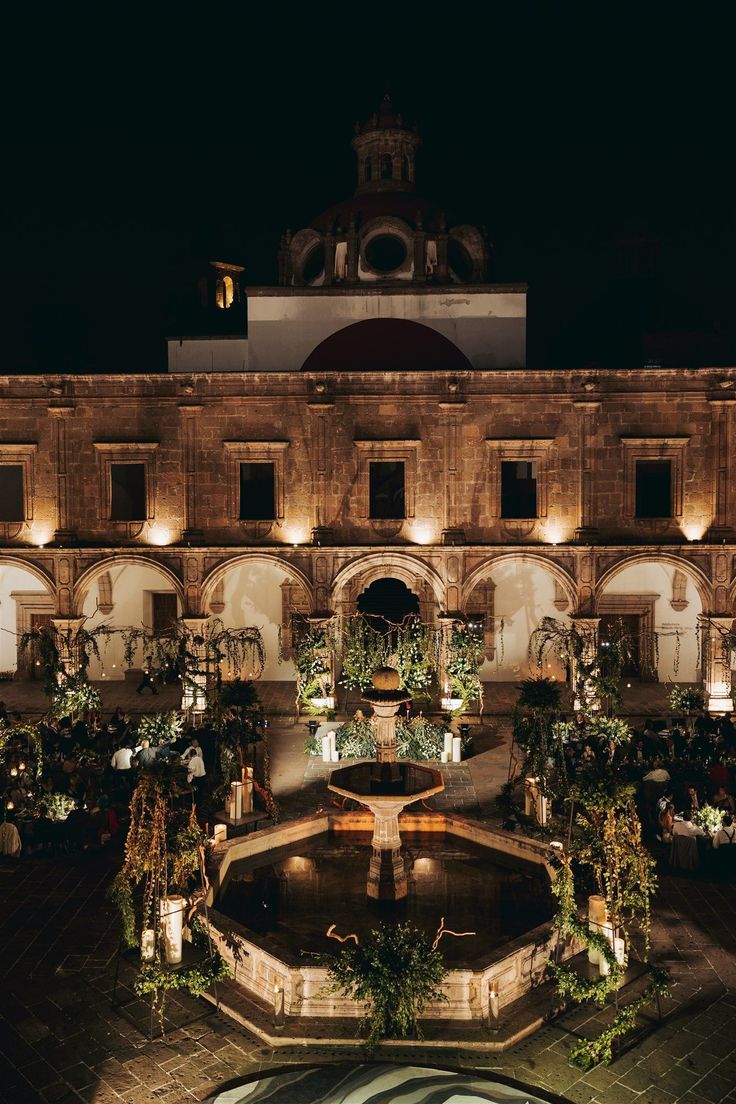 an illuminated courtyard with fountains and potted plants