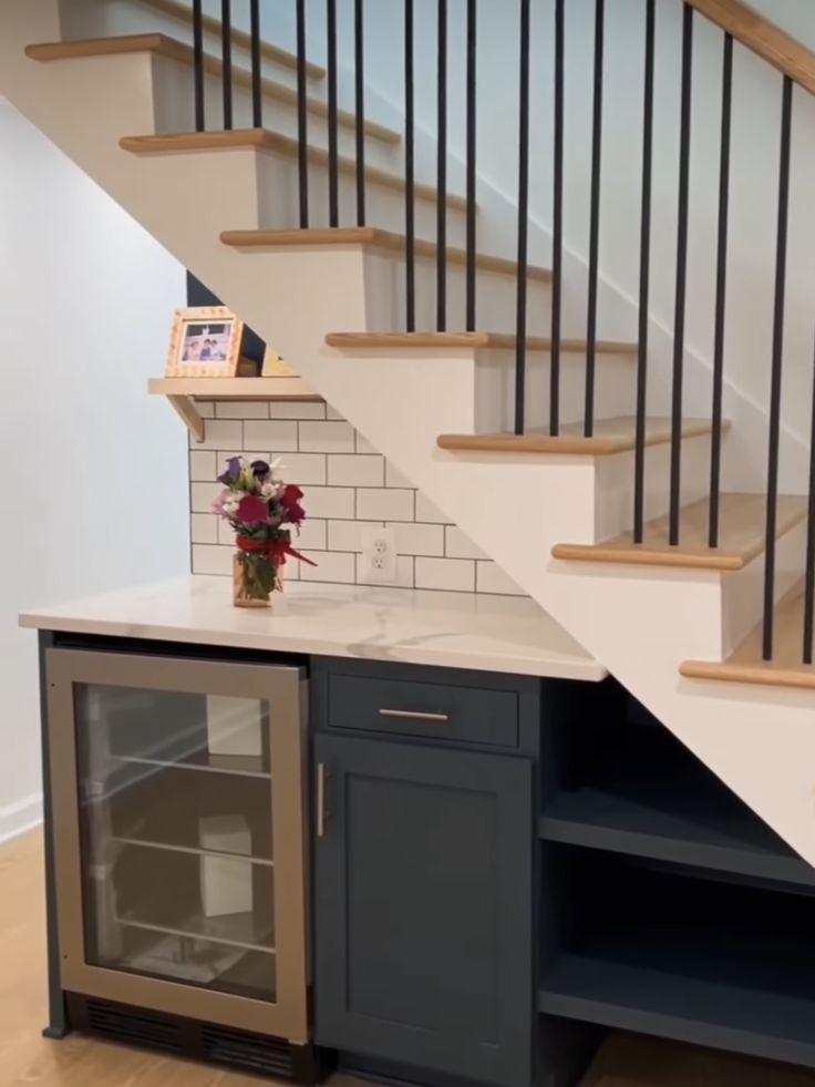 a kitchen area with an open cabinet under the stairs