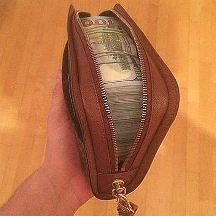 a hand holding a wallet with money in it and a keychain attached to it