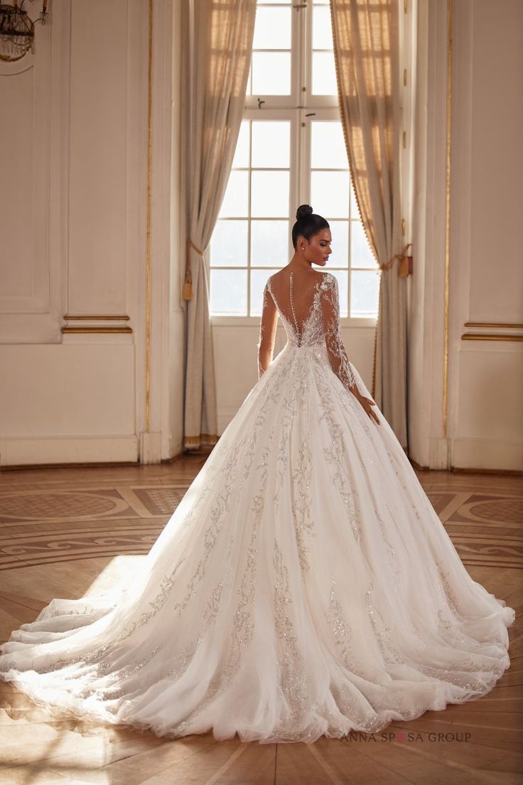 a woman in a wedding dress is standing by a window with her back to the camera