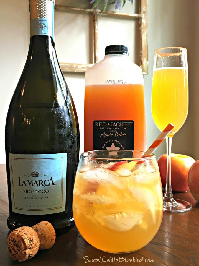 two bottles of wine, an orange juice and some fruit are sitting on a table