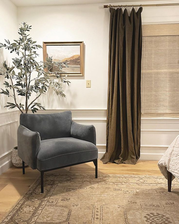 a living room with a couch, chair and rug in front of a window that has drapes on it