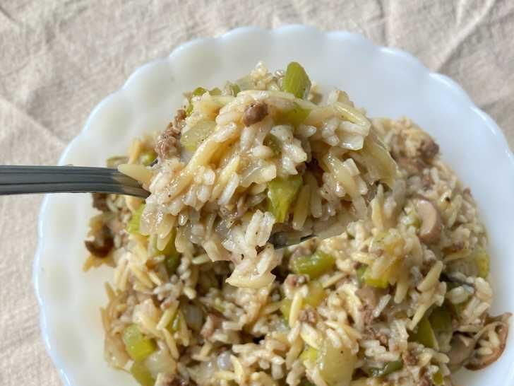 a white plate topped with rice covered in meat and veggies next to a fork