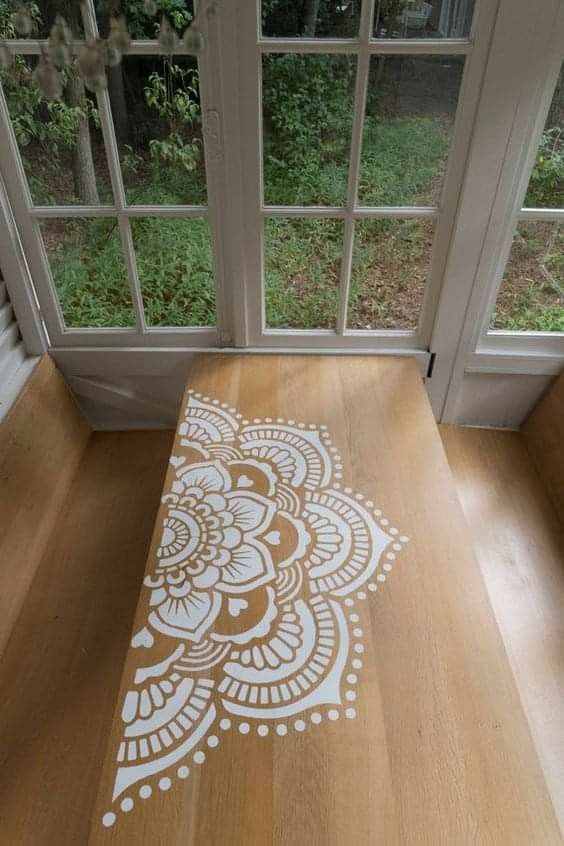 a wooden table with an intricate stencil design on it in front of a window