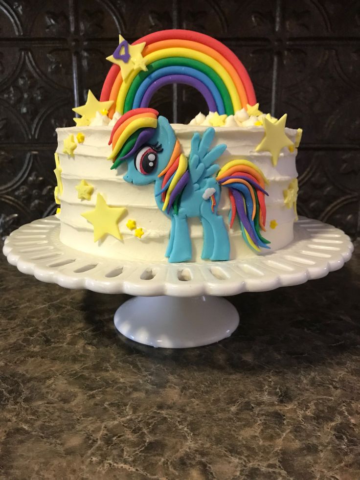 a white cake topped with rainbows and stars on top of a counter next to a wall