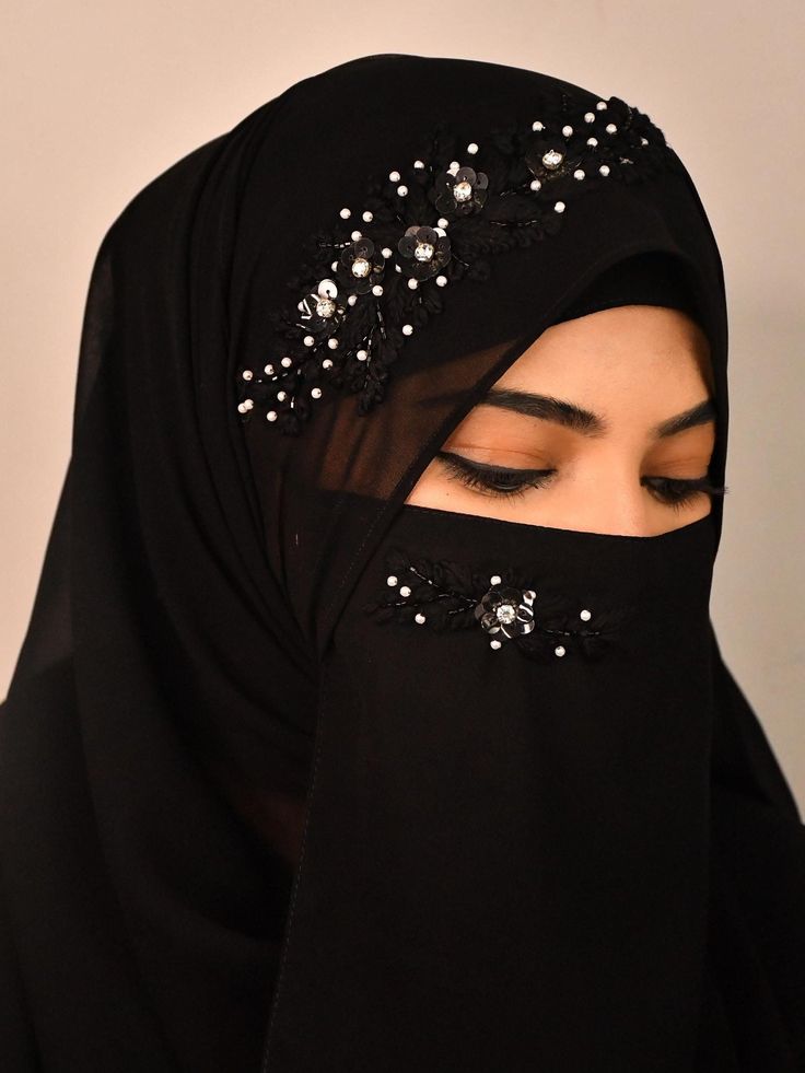 a woman wearing a black hijab with sequins on it