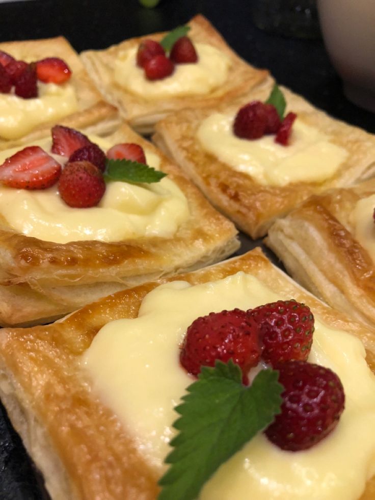 several desserts with strawberries and cream on them sitting on a black counter top