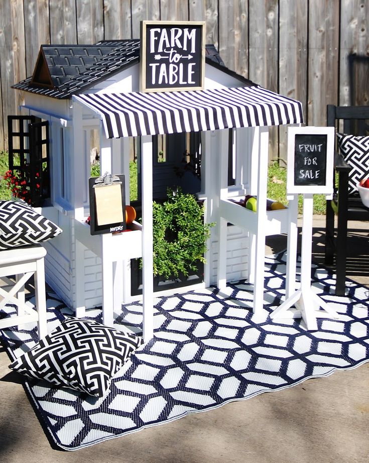 a small white and black gazebo sitting on top of a rug next to a wooden fence