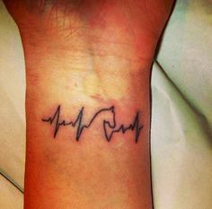 a woman's wrist with a heartbeat tattoo on it