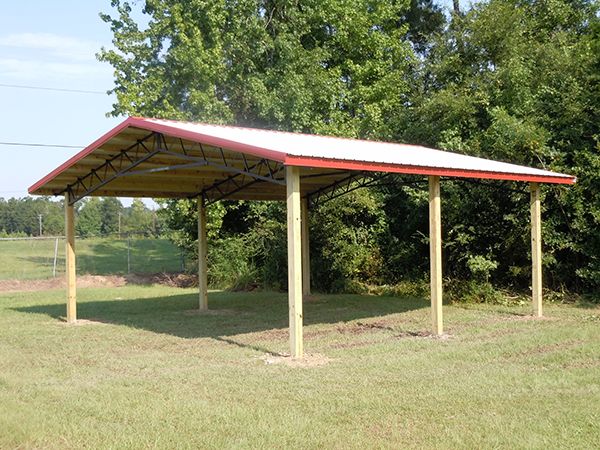 a red and white covered structure in the middle of a field with trees behind it