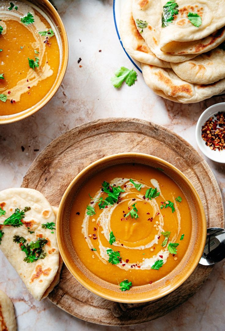 bowls of soup and pita bread on a table