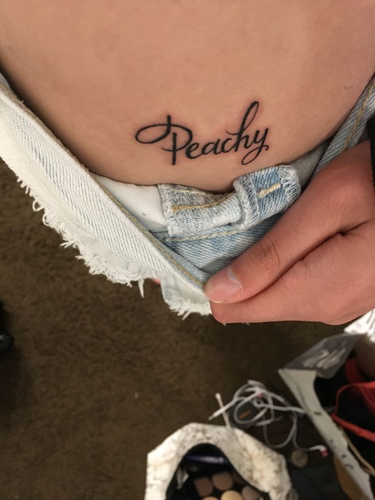 a woman's stomach with the word peachy tattooed on it