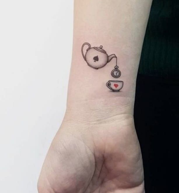 a small wrist tattoo with a teapot and cup on the left side of it