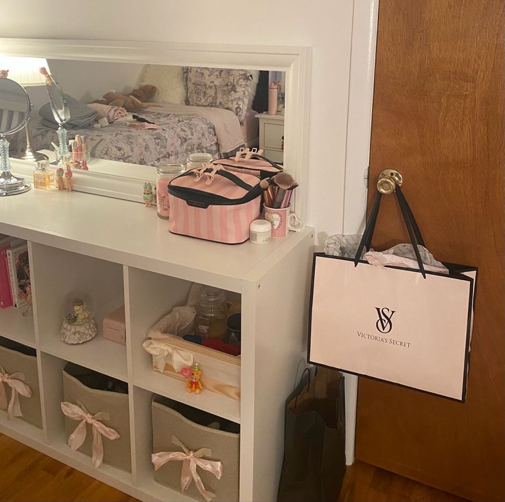 there is a white shelf with many items on it and a bag hanging from the wall