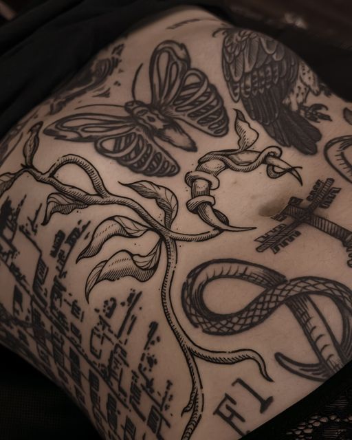 the back of a woman's stomach with tattoos on it and an eagle, snake, cross