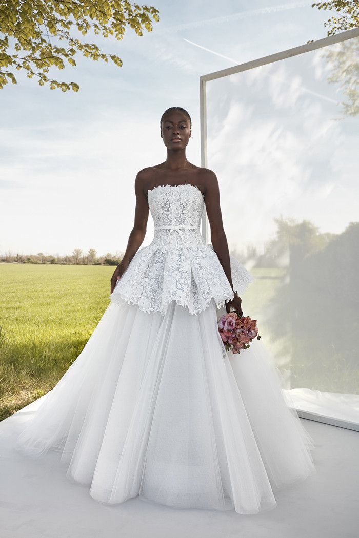 a woman standing in front of a mirror wearing a wedding dress with ruffles