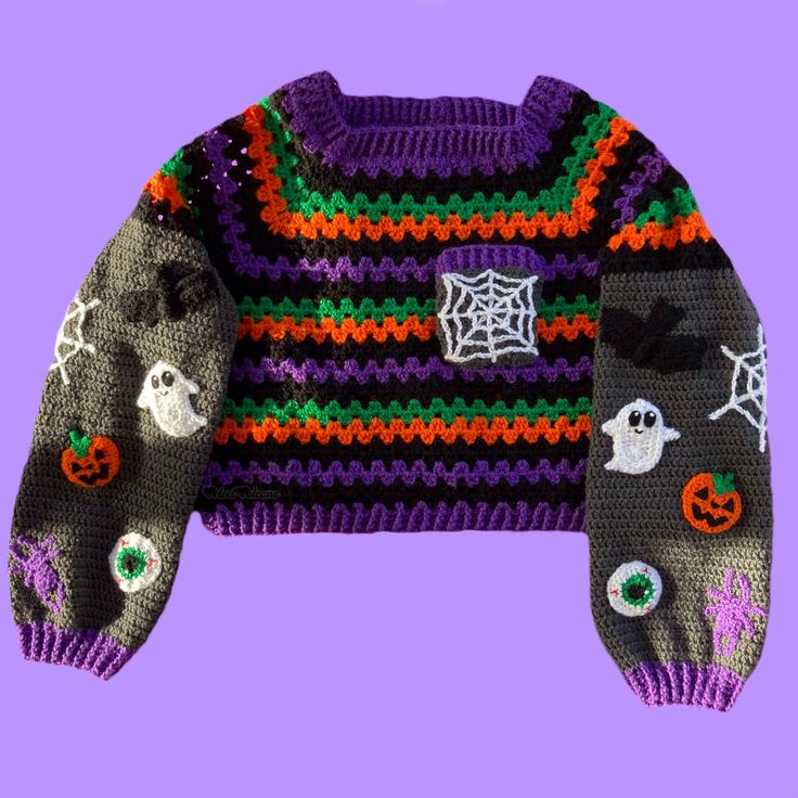 a knitted sweater with halloween decorations and ghost eyes on it, against a purple background