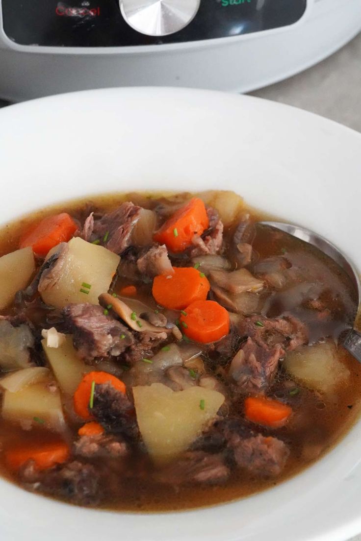 a white bowl filled with meat and vegetables next to an instant pressure cooker in the background