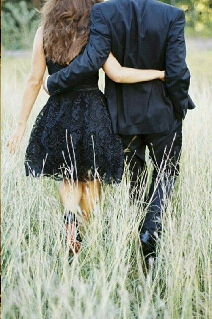 a man and woman walking through tall grass