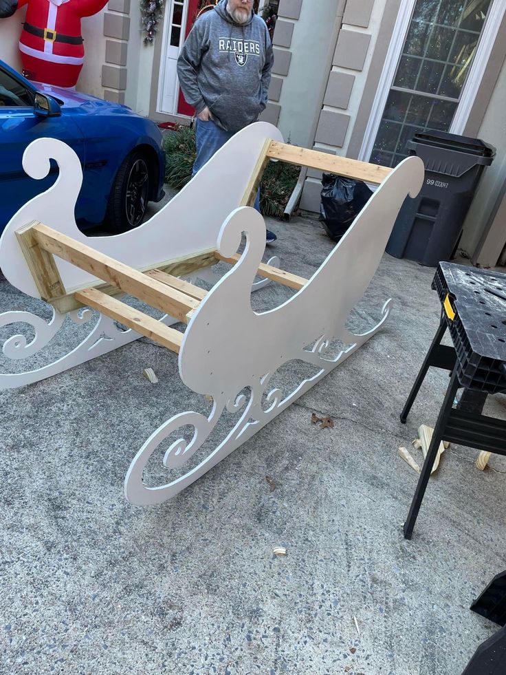 a man standing next to a sleigh made out of wood and plywood