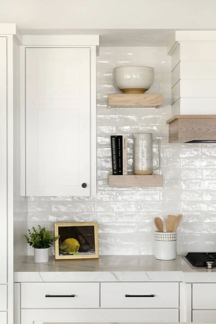 a kitchen with white cabinets and wooden shelves