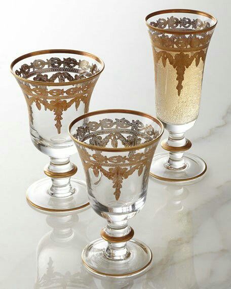 three glass goblets sitting on top of a white table next to each other