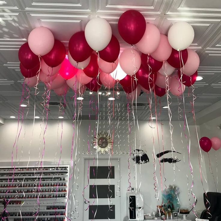 balloons and streamers are hanging from the ceiling in an office space with white walls