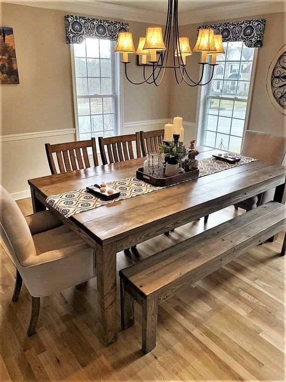 a dining room table and bench in front of two windows