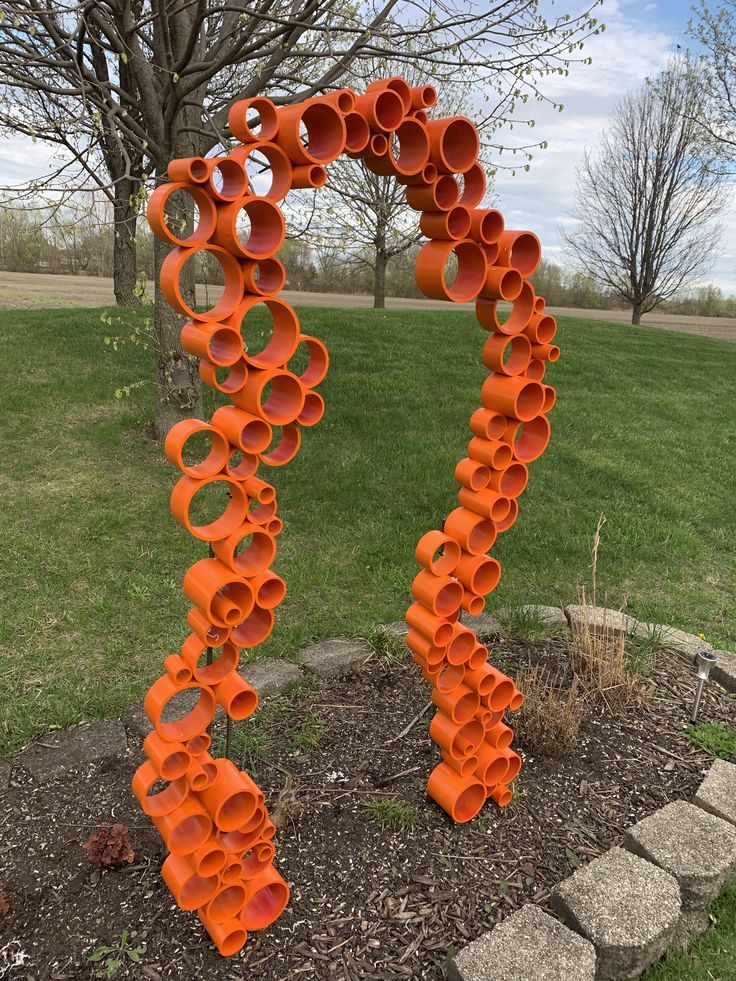 an orange sculpture in the middle of a park