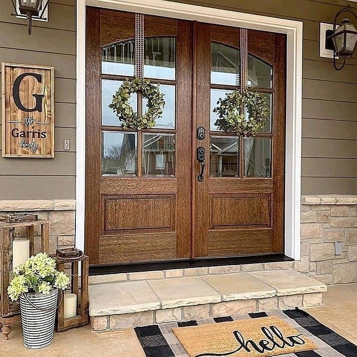 the front door is decorated with wreaths and two large wooden doors that are open