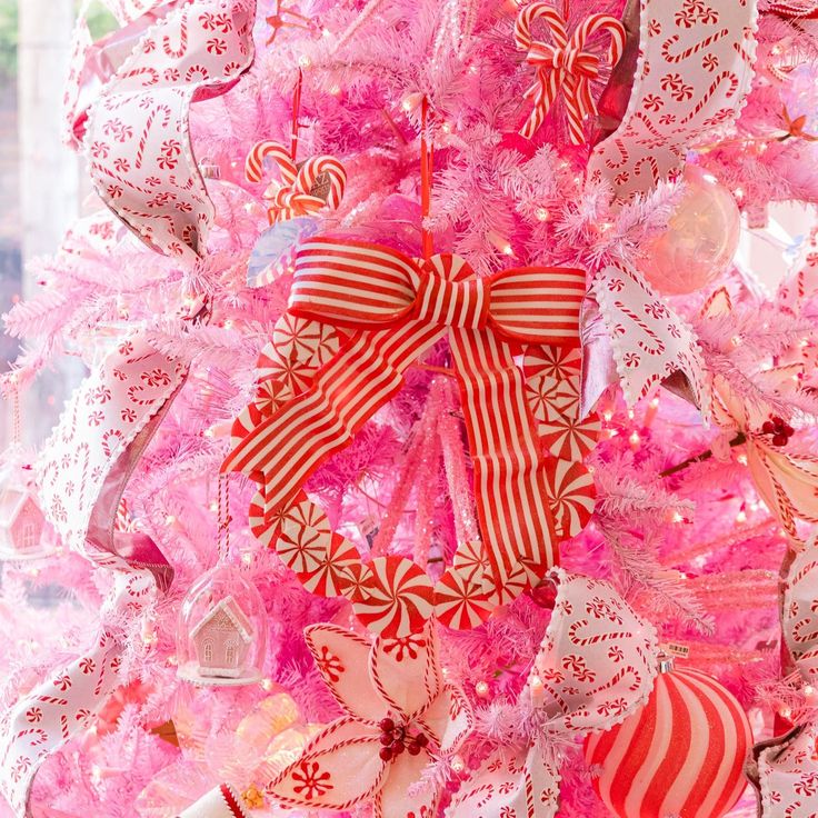 a pink christmas tree decorated with candy canes and bows