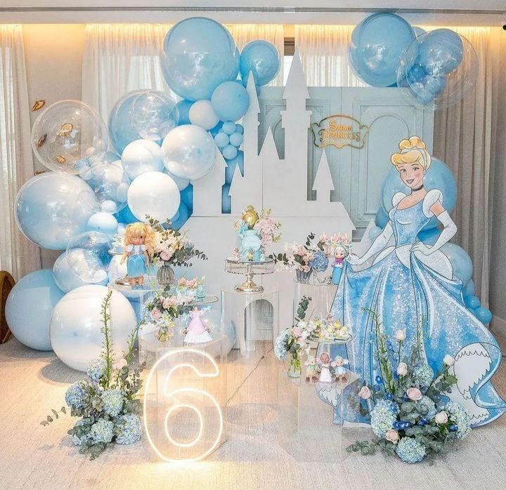 there are balloons and decorations on the floor in front of a backdrop with princesses