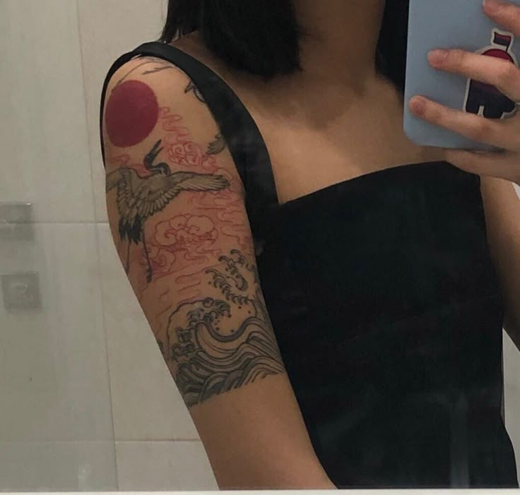 a woman with a tattoo on her arm holding a cell phone