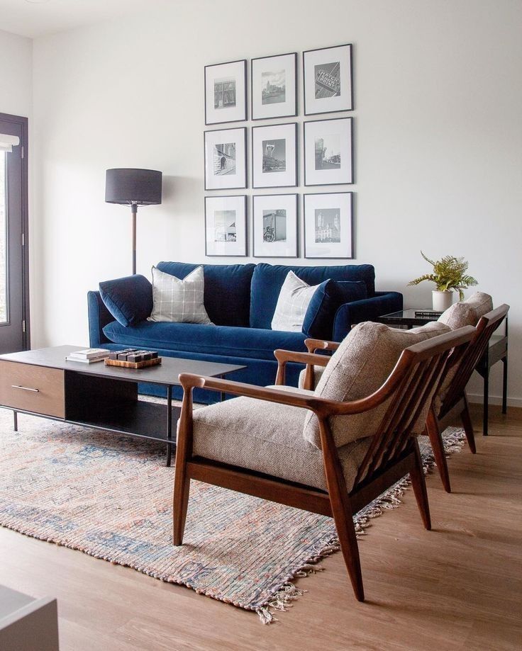 a living room with blue couches and pictures on the wall above them, along with a coffee table