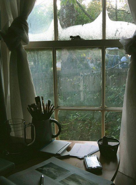 an open book on a desk in front of a window with rain coming through it