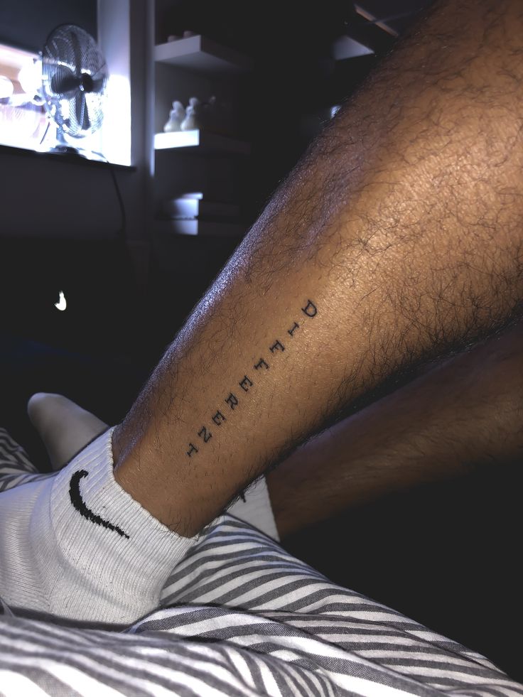 a man's leg with the word strength tattooed on his lower arm and foot