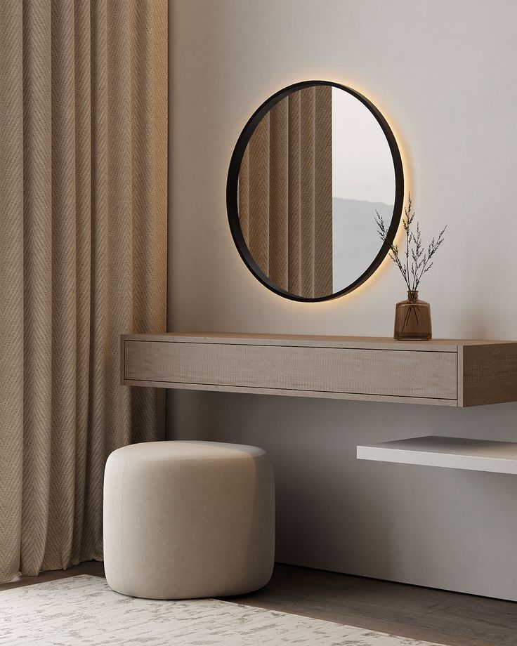 a round mirror sitting on top of a wooden table next to a white stool and window