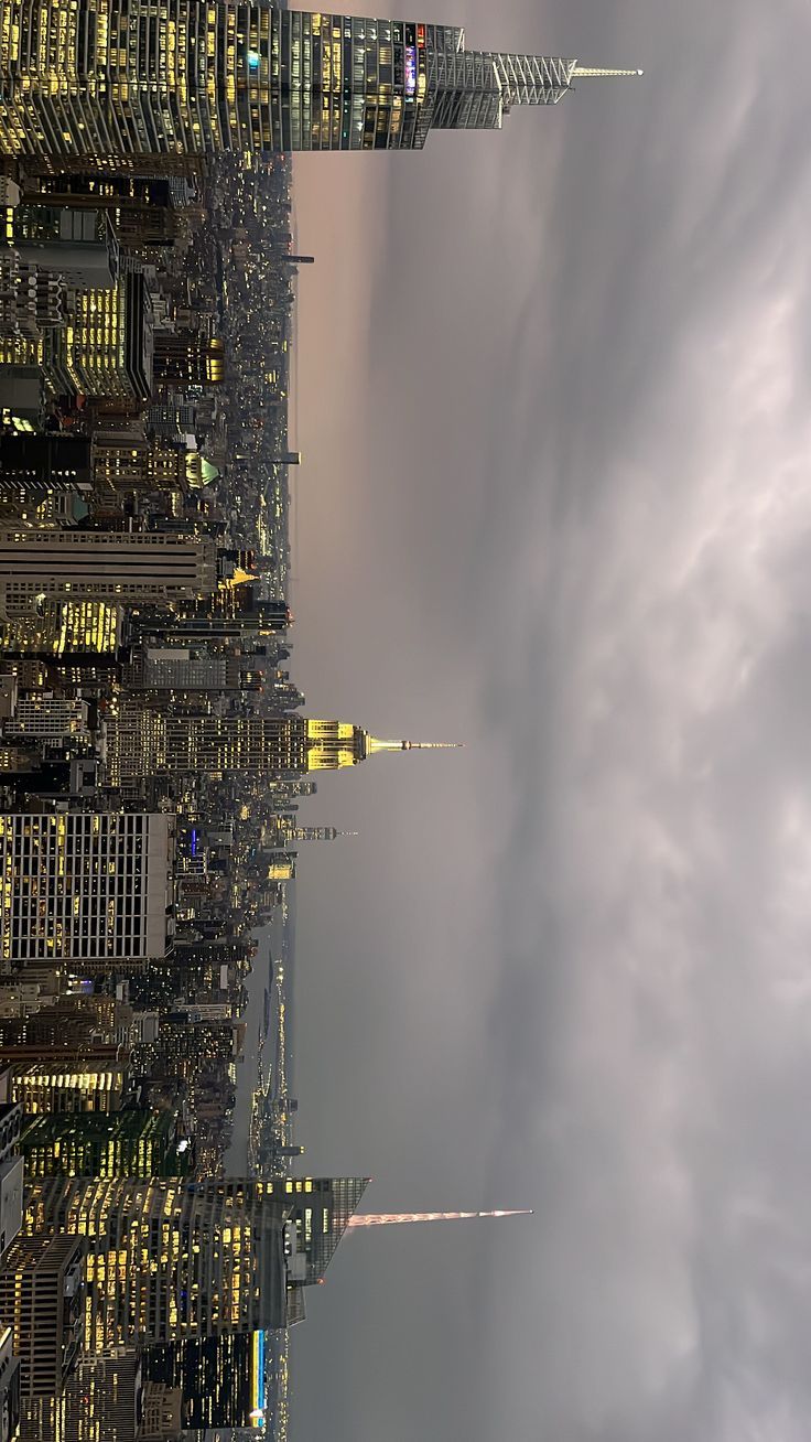 an image of the city skyline at night with clouds in the sky and skyscrapers lit up