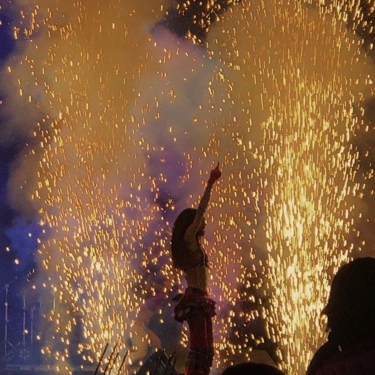 people watching fireworks in the night sky with their hands up and one person reaching up