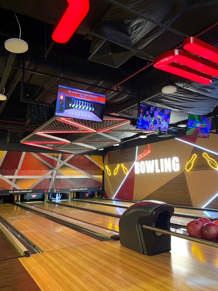 bowling alley with neon lights and bowling balls on the sidelines in an indoor facility